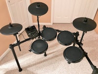 a black drum set sitting on a floor in a room